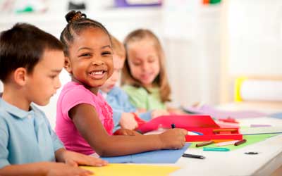 A kid smiling at the camera while doing a fun activity at a preschool in Pataskala Ohio